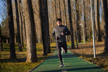 Foto de Atleta maduro corriendo en el parque en un frío y soleado día de invierno - Imagen libre de derechos
