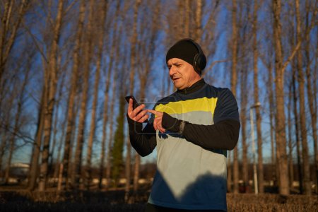 Téléchargez les photos : Runner homme avec écouteurs choisir sa playlist avant de courir - en image libre de droit