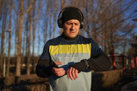 Foto de Runner hombre configurar su smartwatch antes de correr con auriculares - Imagen libre de derechos