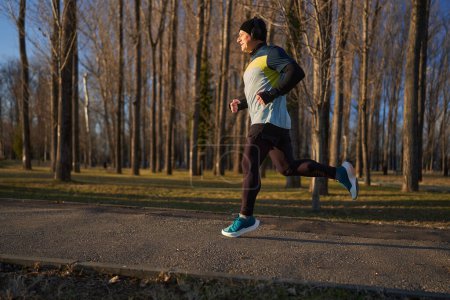 Téléchargez les photos : Runner homme jogging dans un parc dans un froid ensoleillé Décembre jour - en image libre de droit