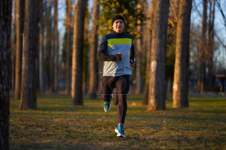 Photo for Mature athlete running in the park in a cold sunny winter day - Royalty Free Image