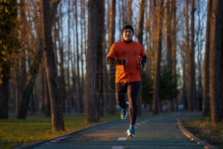 Photo for Athletic man joggin in park at sunset in a cold winter day - Royalty Free Image