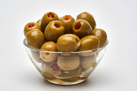 Téléchargez les photos : Grandes olives vertes dénoyautées et remplies de poivre en saumure, dans un petit bol, isolées sur fond blanc - en image libre de droit