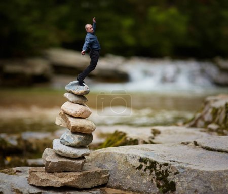 Téléchargez les photos : Homme d'affaires perdant l'équilibre au-dessus d'une pile de pierres zen, techniques mixtes conceptuelles de l'instabilité dans les affaires - en image libre de droit