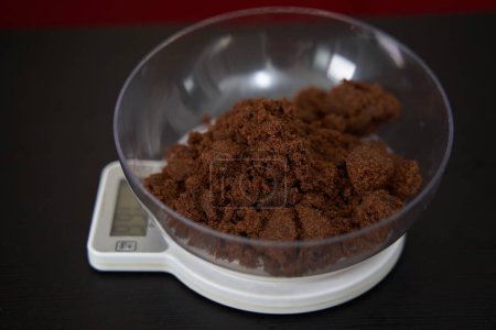 Photo for Weighing muscovado sugar on a kitchen scale - Royalty Free Image