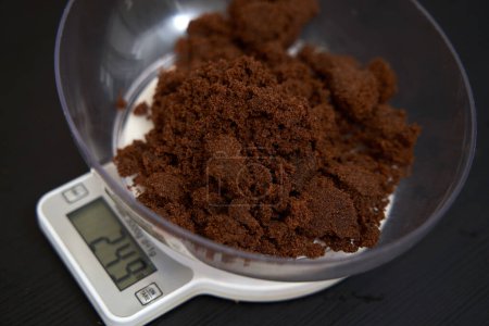 Photo for Weighing muscovado sugar on a kitchen scale - Royalty Free Image