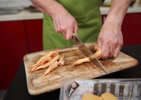 Foto de El hombre cocina la eliminación de las puntas de las alas de pollo y cortarlas por la mitad para una receta - Imagen libre de derechos