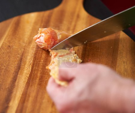 Closeup of cook removing chicken skin from wings for a recipe without cholesterol