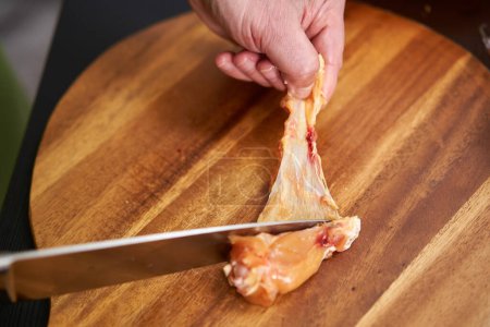 Primer plano de cocinar la eliminación de la piel de pollo de las alas para una receta sin colesterol
