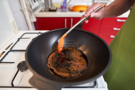 Foto de Primer plano del azúcar caramelizado de moscovado del chef en un wok grande en una estufa - Imagen libre de derechos