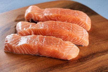 Photo for Raw salmon steak fillets on a wooden board, ready for grill - Royalty Free Image