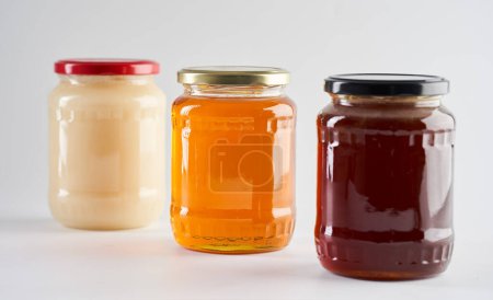 Jars with various types of honey, including honeydew or forest honey, wild flowers honey and canola honey
