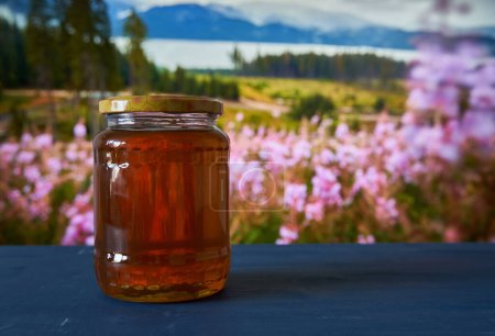 Honey in jars on wooden board in beautiful mountain view with flowers