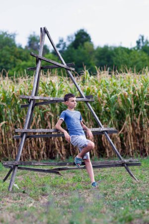 Photo for Happy child leaning on a hay stack support near a corn field - Royalty Free Image