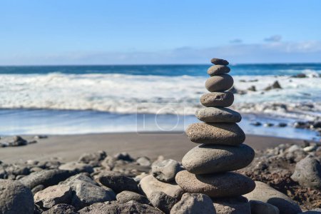 Téléchargez les photos : Empilement de pierres zen sur la plage de l'océan par une journée ensoleillée - en image libre de droit