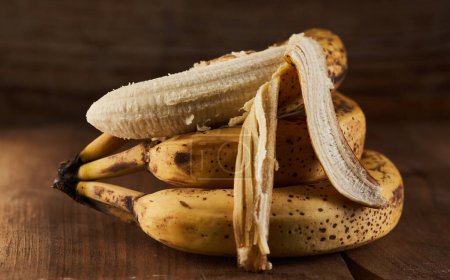 Téléchargez les photos : Bouquet de bananes sucrées trop mûres sur une planche en bois rustique - en image libre de droit