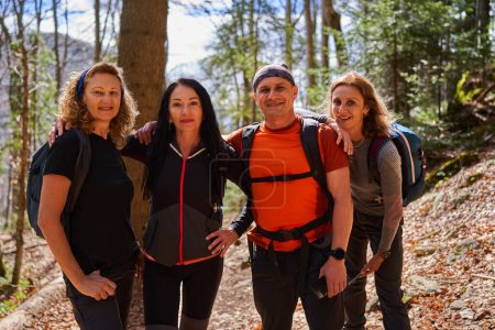 Photo for Mixed group of hikers with a man and three women with backpacks on a trail in the highlands - Royalty Free Image