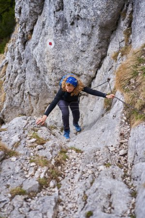 Foto de Mujer montañista escalando una pared empinada en la línea de seguridad - Imagen libre de derechos