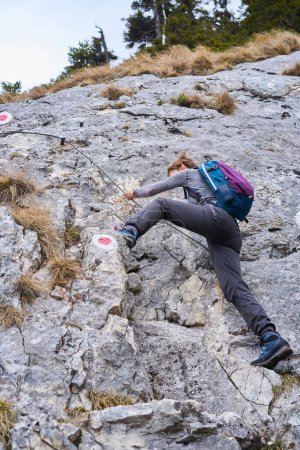 Téléchargez les photos : Femme alpiniste escalade un mur escarpé sur la ligne de sécurité - en image libre de droit