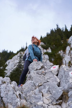 Téléchargez les photos : Femme alpiniste se reposant après une montée difficile sur une montagne escarpée - en image libre de droit