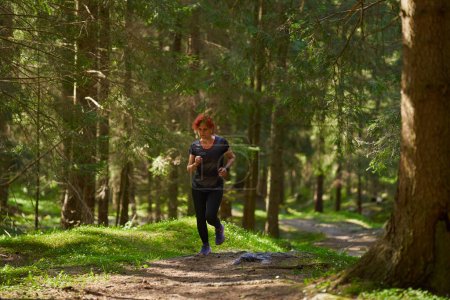 Photo for Redhead woman trail runner training in the forest running uphill - Royalty Free Image