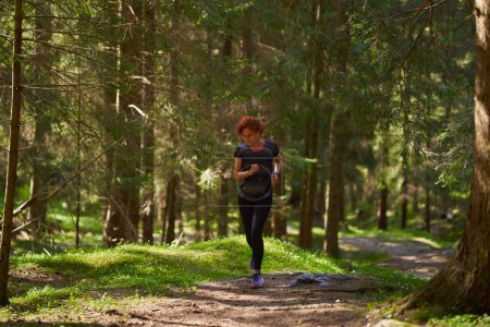 Foto de Pelirroja mujer trail runner entrenamiento en el bosque corriendo cuesta arriba - Imagen libre de derechos