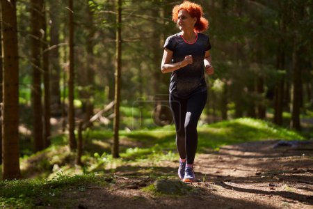 Téléchargez les photos : Rousse femme trail runner entraînement dans la forêt course en montée - en image libre de droit