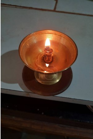 View of lighted, brass oil lamp with oil and cotton wicks used during puja