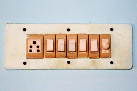 View of an old electrical switch board fixed on painted wall in room