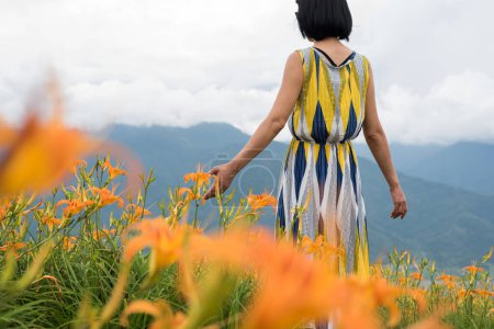 Photo for Asian woman feel free and stand in the yellow tiger lily farm - Royalty Free Image