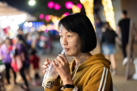 Téléchargez les photos : Femme asiatique tenant la célèbre bulle taïwanaise thé au lait sur le marché de nuit - en image libre de droit