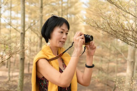 Photo for Modern Asian woman hold a camera in the forest - Royalty Free Image