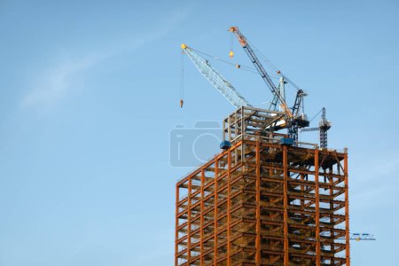 Téléchargez les photos : Grue de construction sur le sommet du gratte-ciel de la ville contre le ciel bleu - en image libre de droit