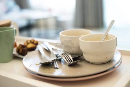 Photo for Scene after dining in a hotel room, with used plates and cutlery. - Royalty Free Image