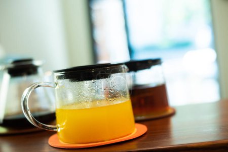 Foto de Tres macetas de vidrio que contienen té, café y jugo están sobre la mesa. - Imagen libre de derechos