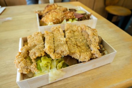 Téléchargez les photos : Boîte à lunch de côtelette de porc frit sur la table dans un restaurant chinois - en image libre de droit