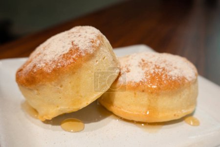Téléchargez les photos : Petits pains en poudre saupoudrés de sucre sur une assiette blanche, à l'intérieur. - en image libre de droit