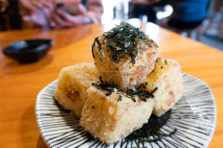Photo for Fried tofu cubes garnished with seaweed flakes on a patterned plate. - Royalty Free Image
