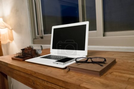 Foto de Trabajar en casa con portátil en la mesa de madera en la noche - Imagen libre de derechos