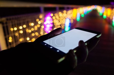 Foto de Mujer sostener un teléfono celular con pantalla blanca en blanco por la noche - Imagen libre de derechos