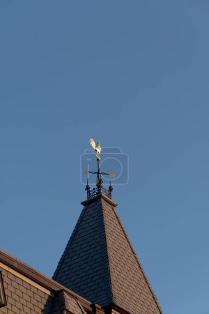 Photo for Rooster Windvane on Conical Roof on Blue Sky - Royalty Free Image