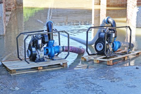 Zwei Benzinmotorpumpen an Frachtpaletten pumpen Wasser aus überfluteter Passage ab