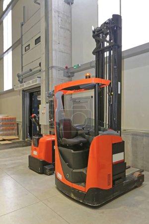 Photo for Electric Forklift and Pallet Truck Parked in Distribution Warehouse - Royalty Free Image