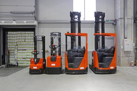 Photo for Four Vehicles Pallet Trucks and Forklifts in Distribution Warehouse - Royalty Free Image