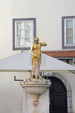 Foto de Liubliana, Eslovenia - 12 de octubre de 2014: Estatua dorada de una niña con una fuente de agua en la plaza Riblji en el centro histórico de la ciudad. - Imagen libre de derechos