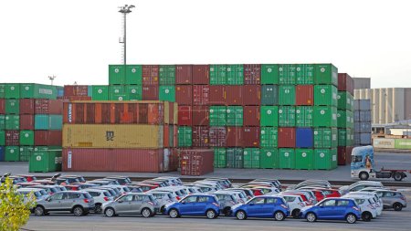 Foto de Koper, Eslovenia - 14 de octubre de 2014: Vehículos nuevos y contenedores de carga en el sistema logístico del puerto terminal. - Imagen libre de derechos