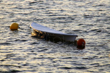 Téléchargez les photos : Une planche à pagaie flottant dans l'eau au coucher du soleil. - en image libre de droit