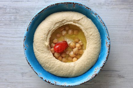 Photo for A Lebanese traditional plate of hummus with lots of olive oil, chickpeas, and a cherry tomato. - Royalty Free Image