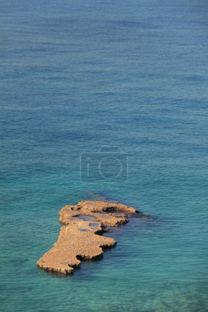 Téléchargez les photos : Un rocher dans la mer Méditerranée de Batroun ressemblant à distance à la carte de Liban. - en image libre de droit