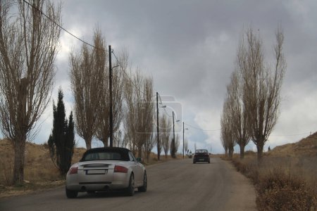 Téléchargez les photos : Deux voitures conduisent par une journée froide sur une route désolée. - en image libre de droit